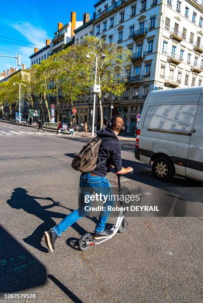 Jeune homme circulant en trottinette électrique en libre service sur la chaussée tout en portant un casque pour écouter de la musique le 17 avril...