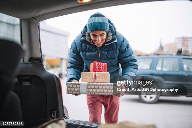 hombre adulto cargando regalos de navidad en el maletero del coche. - día de las cajas fotografías e imágenes de stock