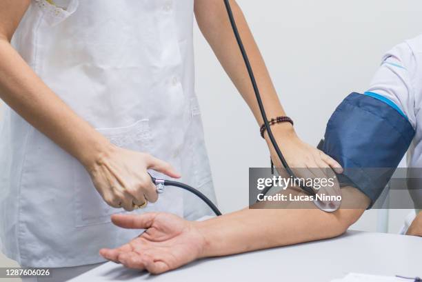 doctor measuring patient blood pressure - hypertension stock-fotos und bilder