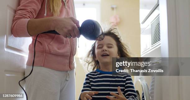 mother blow cold air with a hair dryer to her three year old son - mother son shower stockfoto's en -beelden