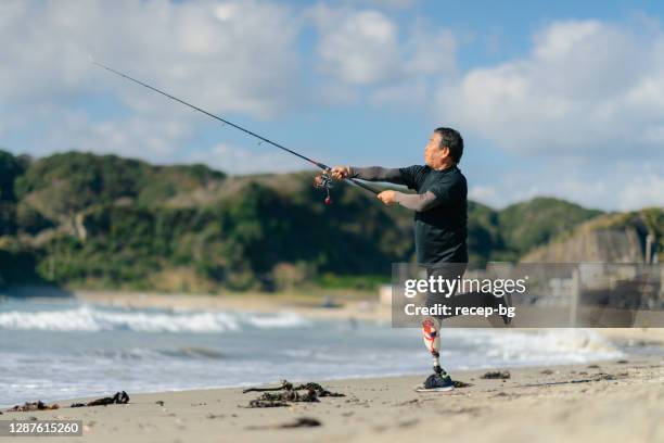 ビーチで人工脚釣りを持つシニア大人の男性 - fishing ストックフォトと画像