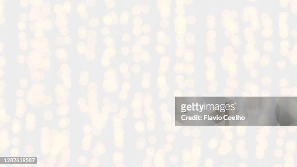 defocused fairy lights hanging on white wall background - christmas lights isolated stock-fotos und bilder