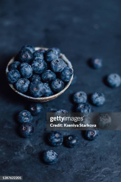 plate with blueberries spilled on blue background - blackberry fruit stock pictures, royalty-free photos & images