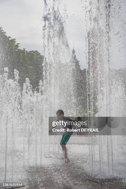 Un enfant profite de la fraicheur des jets d'eau de la place Bellecour lors de la canicule le 25 Juin 2019 à Lyon, France