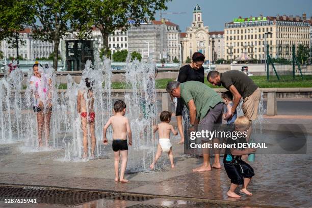 Des habitants avec leurs enfants profitent de la fraicheur des jets d'eau de la place Bellecour lors de la canicule le 25 Juin 2019 à Lyon, France