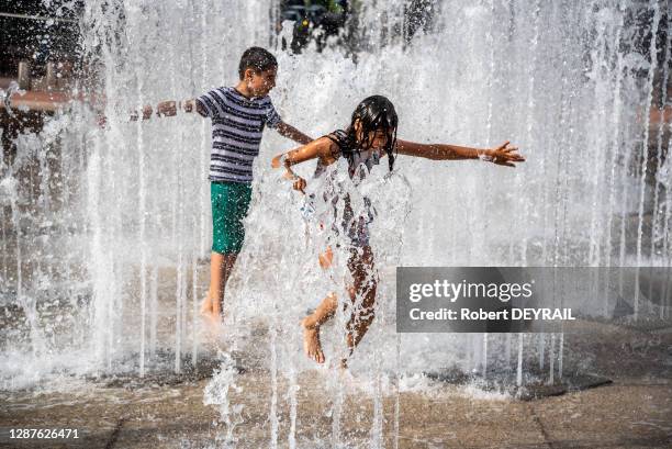 Les enfants profitent de la fraicheur des jets d'eau de la place Bellecour lors de la canicule le 25 Juin 2019 à Lyon, France