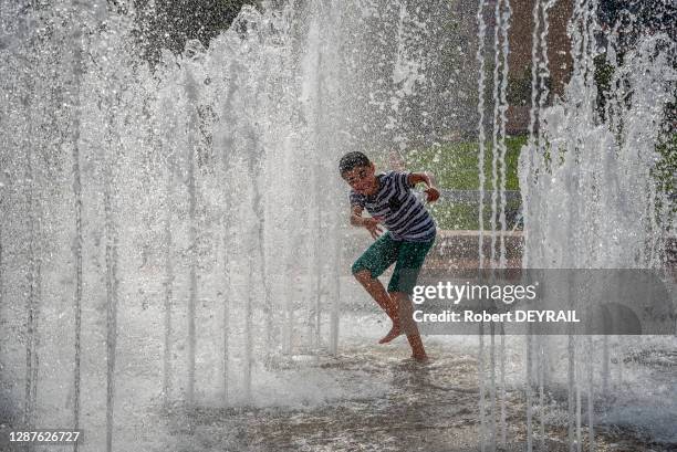 Un enfant profite de la fraicheur des jets d'eau de la place Bellecour lors de la canicule le 25 Juin 2019 à Lyon, France