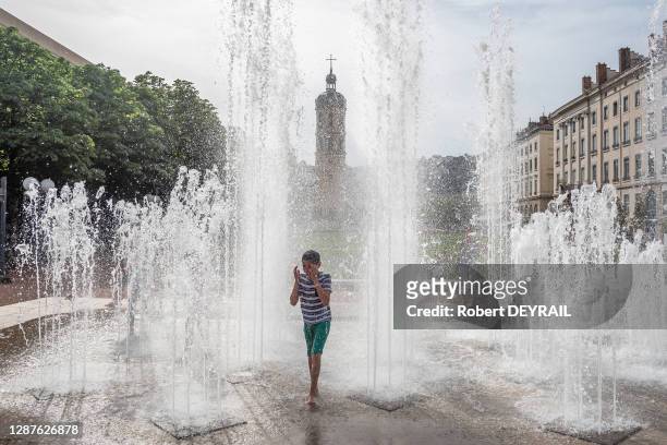 Un enfant profite de la fraicheur des jets d'eau de la place Bellecour lors de la canicule le 25 Juin 2019 à Lyon, France