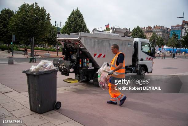 Eboueur ollectant des déchets et camion poubelle le 24 juin à Ternay, France.