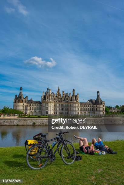 Randonneurs à vélo se reposant sur l'herbe des jardins du château de Chambord, France, le 21 mai 2019.