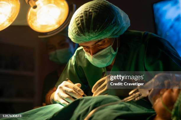 surgeons operating patient for breast implant. team of doctors are in scrubs at operating room. - chirurgo plastico foto e immagini stock