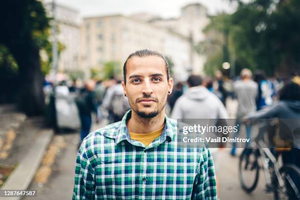 porträt eines jungen kaukasier / gemischten rassenmannes in der stadt. junger mann schaut direkt in die kamera. - streik stock-fotos und bilder