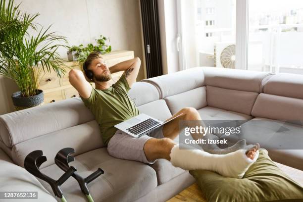 young man with broken leg resting at home - broken leg stock pictures, royalty-free photos & images