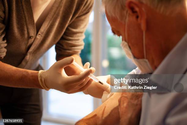 medical home visit: senior man receiving injection/vaccination - flu vaccine foto e immagini stock