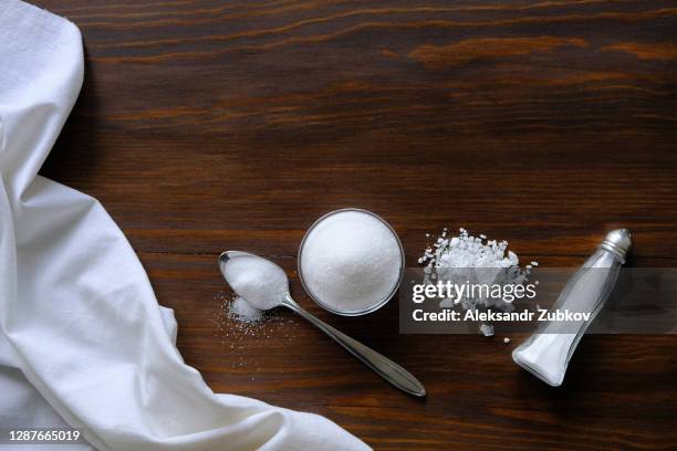 natural, organic, sea, white salt in a spoon, in a cup, in a salt shaker, poured on a wooden table. next to the linen towel. the concept of cooking healthy food, cosmetology. selective focus - zout smaakstof stockfoto's en -beelden