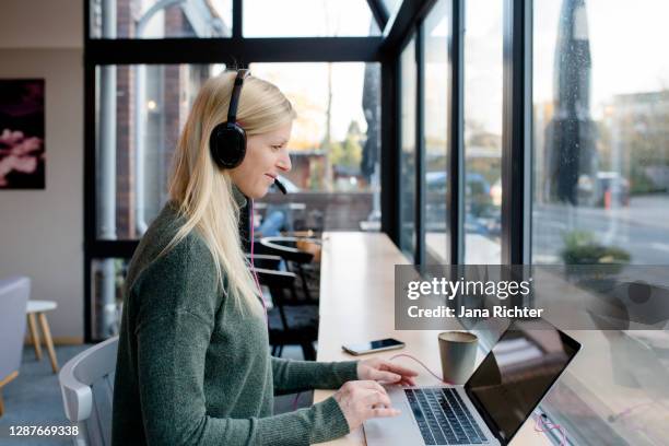 woman sitting in cafe with headset - germany training press conference stock pictures, royalty-free photos & images