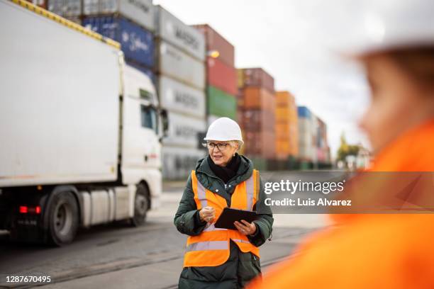 senior woman working at large commercial dock - dock worker stock-fotos und bilder