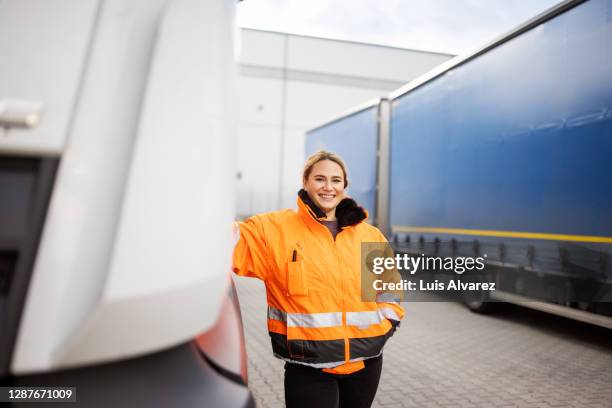female transport engineer standing by the truck outdoors - arbeitskleidung stock-fotos und bilder
