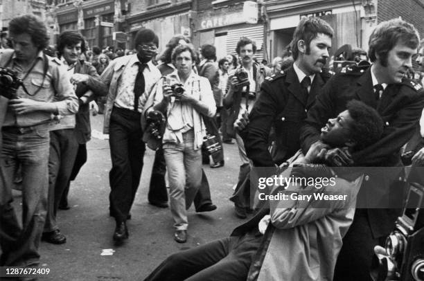 Photographers follow a police officer as he holds a demonstrator in a headlock and drags him away, during a National Front march in London, England,...