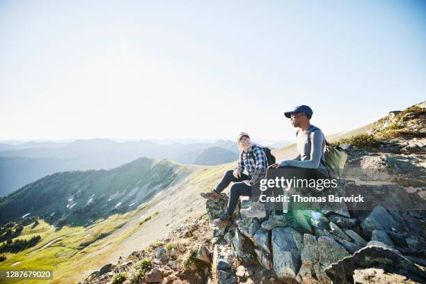 smiling couple hanging out on rocks during early morning hike in mountains - fun sommer berge stock-fotos und bilder