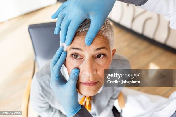 paciente de alto nivel que se somete a un examen ocular en el consultorio del oftalmólogo - ophthalmologist fotografías e imágenes de stock