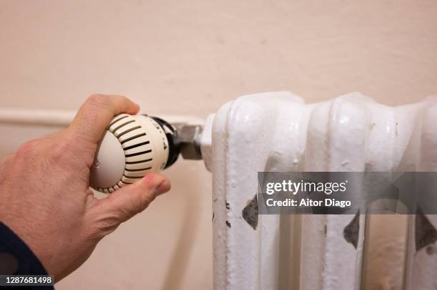 person adjusting the temperature of a radiator. - heizung stock-fotos und bilder