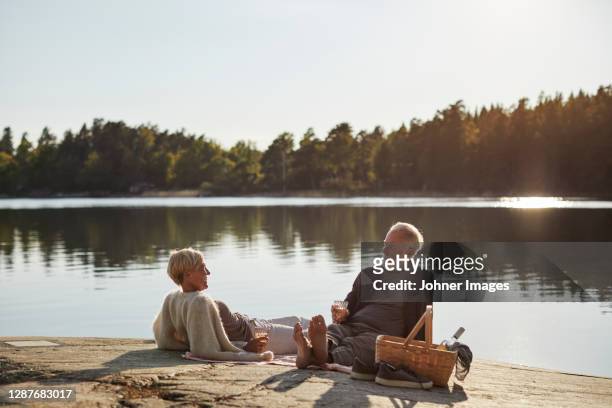 smiling couple having picnic at lake - summer picnic stockfoto's en -beelden