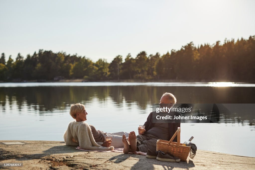Smiling couple having picnic at lake
