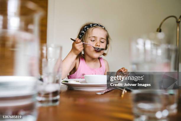 girl eating at table - soup on spoon imagens e fotografias de stock