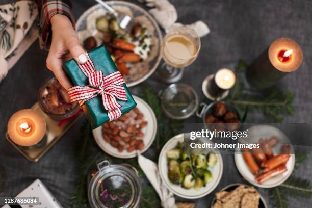 hand holding christmas gift over table with food - johner images bildbanksfoton och bilder