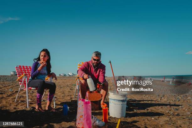 father and daughter eating on a patagonian beach - beach argentina fotografías e imágenes de stock