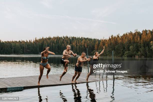 friends jumping into lake - bathing jetty stock pictures, royalty-free photos & images