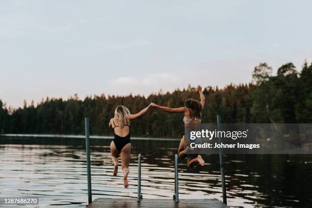 women jumping together into water - woman jumping lake bildbanksfoton och bilder