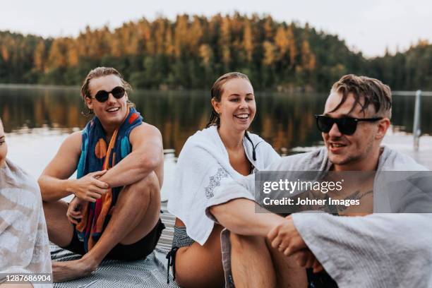 happy friends sitting on jetty - jetty lake stock pictures, royalty-free photos & images