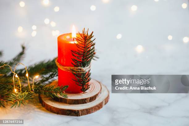 christmas festive winter greeting card. white candle, wooden natural tray and pine fir tree branches. home interior decoration. - christmas candle foto e immagini stock