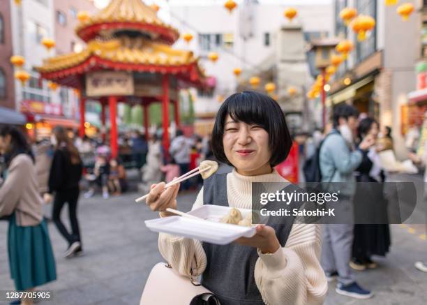 feliz joven comiendo albóndigas al vapor en la calle en chinatown - kobe - japan fotografías e imágenes de stock