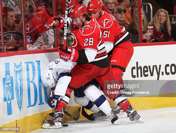 Justin Faulk and Tomas Kaberle of the Carolina Hurricanes get tagled up along the boards with Ryan Shannon of the Tampa Bay Lightning during a NHL...