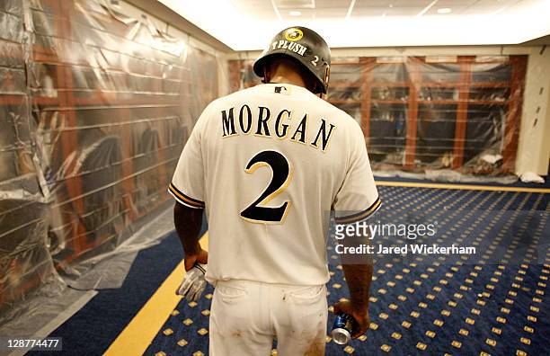 Nyjer Morgan of the Milwaukee Brewers walks around the clubhouse wearing a helmet with the name 'T Plush' on the back following their win against the...