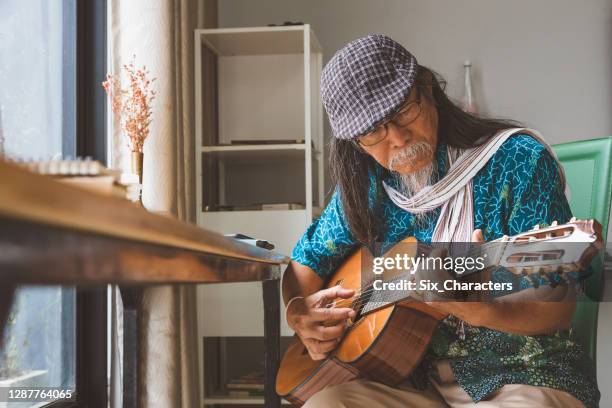 asian senior men enjoy playing guitar in living room at home - musician portrait stock pictures, royalty-free photos & images