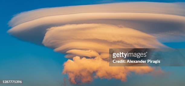 beautiful lenticular clouds illuminated rising of sun in blue sky at sunset in golden hour. stratocumulus clouds - rare natural phenomenon. beautiful panoramic landscape of weather, meteorology background - light natural phenomenon stock pictures, royalty-free photos & images