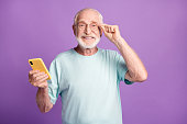 Photo portrait of happy man touching glasses holding phone in one hand isolated on vivid violet colored background