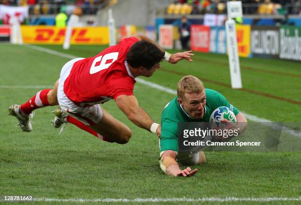 Wing Keith Earls of Ireland dives past Mike Phillips of Wales to score a try during quarter final one of the 2011 IRB Rugby World Cup between Ireland...