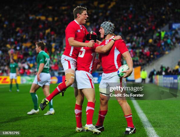 Jonathan Davies of Wales celebrates with teammates Rhys Priestland and Leigh Halfpenny after scoring their third try during quarter final one of the...