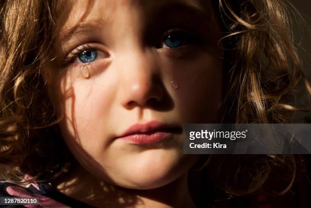 portrait of a sad girl with piercing blue eyes crying - child crying stock-fotos und bilder