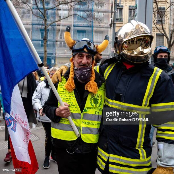Un gilet jaune déguisé en gaulois porte un drapeau français et pose avec un pompier en tenue de feu lors de la manifestation rassemblant 17000...