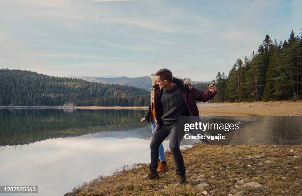 paar genießt im herbst in der nähe von mountain lake - skimming stones stock-fotos und bilder