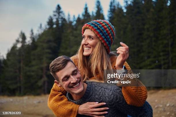 young couple enjoying in autumn near mountain lake - piggyback stock pictures, royalty-free photos & images