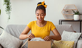 Happy black woman unpacking box after online shopping