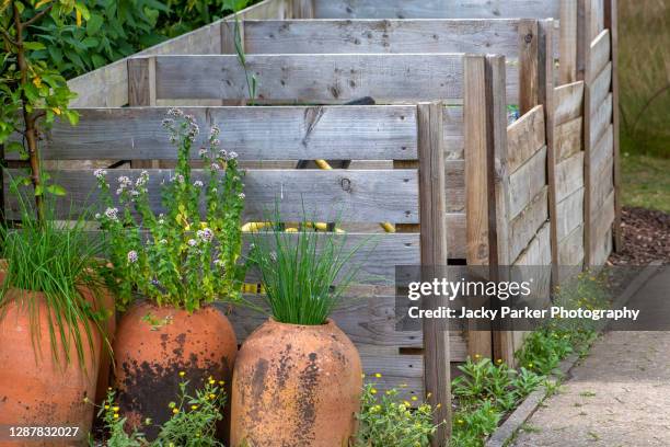 terracotta pots beside wooden/pallet compost bins for composting - compost bin stock pictures, royalty-free photos & images