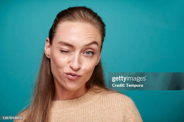 one woman blinking an eye and making a face. - teal portrait stock pictures, royalty-free photos & images